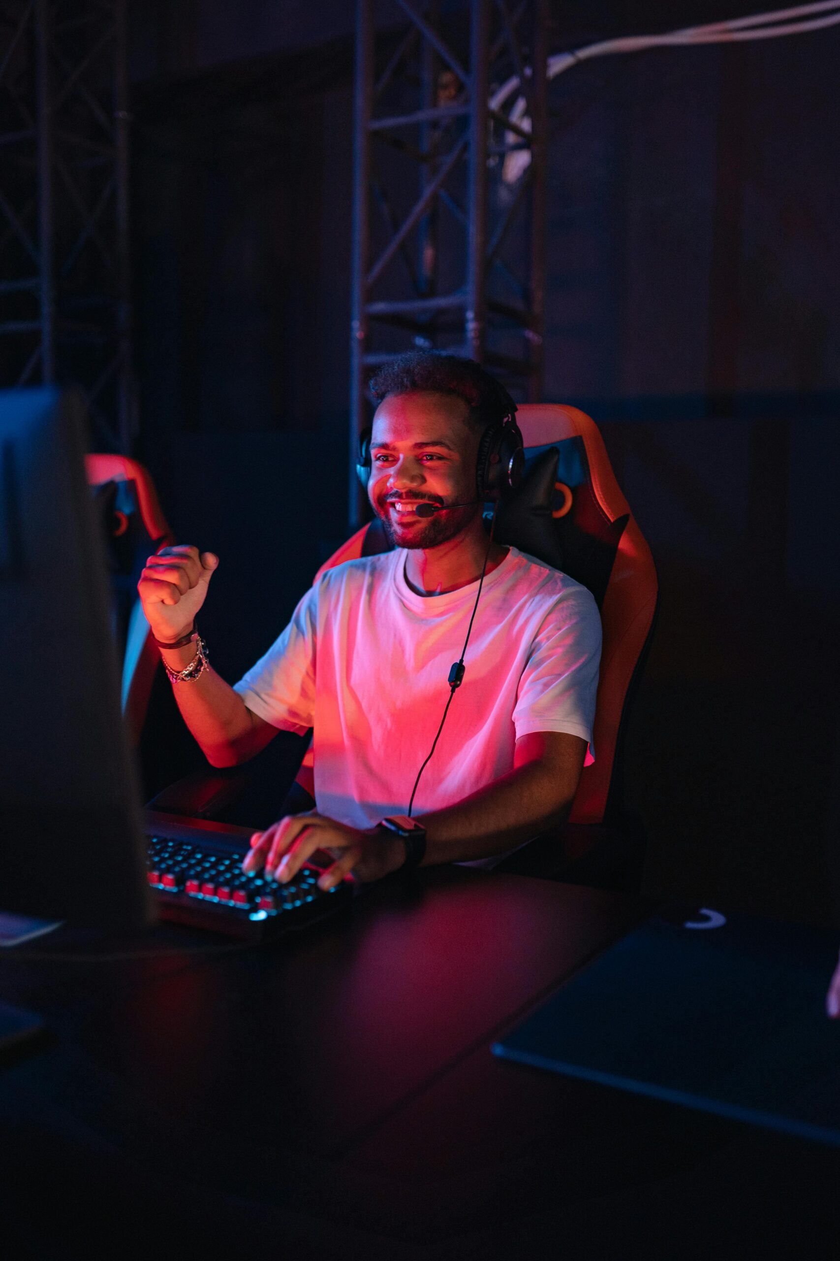 A joyful young man gaming with vibrant RGB lighting in a modern setup.